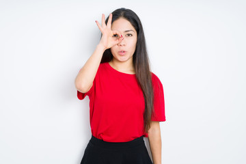 Obraz na płótnie Canvas Beautiful brunette woman wearing red t-shirt over isolated background doing ok gesture shocked with surprised face, eye looking through fingers. Unbelieving expression.
