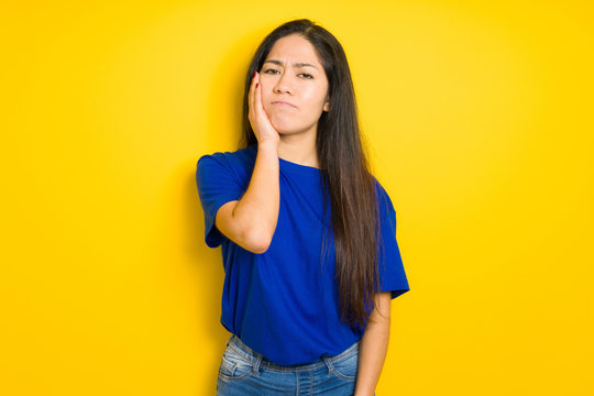 Beautiful brunette woman wearing blue t-shirt over yellow isolated background thinking looking tired and bored with depression problems with crossed arms.