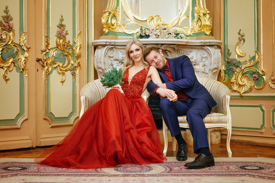 a beautiful woman in a red dress with a man sitting in a chair, the bride and groom, happy newlyweds.