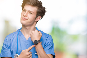 Young doctor wearing medical uniform over isolated background In hurry pointing to watch time,...