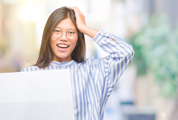 Young asian woman over isolated background holding blank banner stressed with hand on head, shocked with shame and surprise face, angry and frustrated. Fear and upset for mistake.