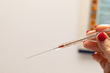 A thin syringe in hand filled up to 10 cc ready to use on a patient or on a test subject