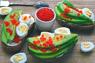 Healthy avocado toasts with red caviar and quail eggs. Tasty and healthy food. Superfoods