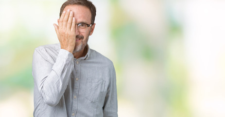 Handsome middle age elegant senior man wearing glasses over isolated background covering one eye with hand with confident smile on face and surprise emotion.