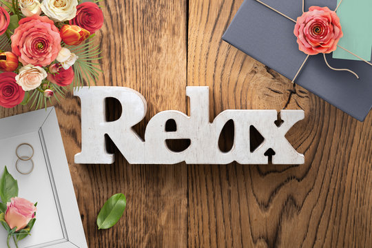 Blumenstrauß und Ringe und das Wort Relax auf Holzuntergrund