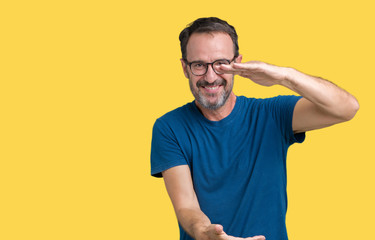 Handsome middle age hoary senior man wearin glasses over isolated background gesturing with hands showing big and large size sign, measure symbol. Smiling looking at the camera. Measuring concept.