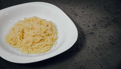 Top view on a white plate with chicken broth on a dark, stone counter top. Dough poured into a plate. Food concept.