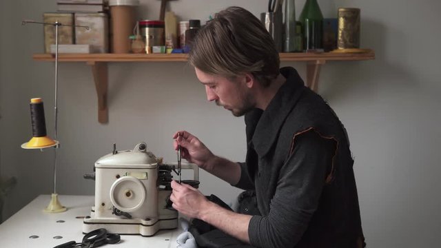 Man tailor sew fur on furrier machine in workshop