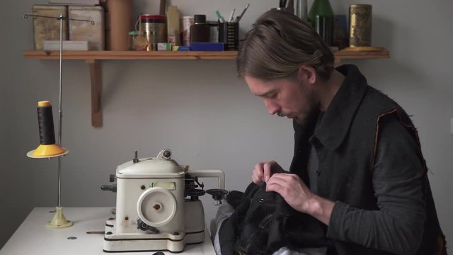 Handsome man tailor working on furrier machine in workshop
