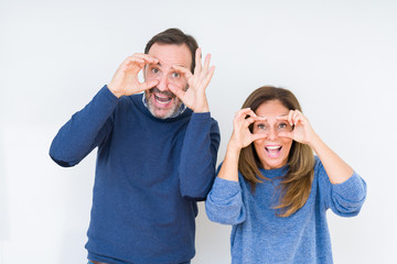 Fototapeta premium Beautiful middle age couple in love over isolated background Trying to open eyes with fingers, sleepy and tired for morning fatigue