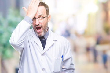 Middle age senior hoary professional man wearing white coat over isolated background surprised with hand on head for mistake, remember error. Forgot, bad memory concept.