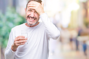 Middle age hoary senior man drinking glass of water over isolated background stressed with hand on head, shocked with shame and surprise face, angry and frustrated. Fear and upset for mistake.