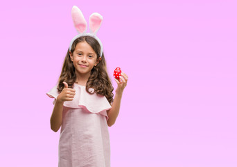 Obraz na płótnie Canvas Brunette hispanic girl wearing easter rabbit ears happy with big smile doing ok sign, thumb up with fingers, excellent sign