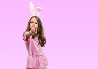 Brunette hispanic girl wearing easter rabbit ears pointing with finger to the camera and to you, hand sign, positive and confident gesture from the front
