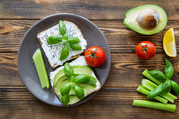 Vegetarian avocado sandwiches with cheese and basil leaves.