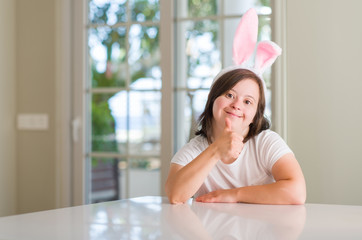 Down syndrome woman at home wearing easter rabbit ears happy with big smile doing ok sign, thumb up...