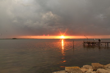 Sunset below dark gray storm clouds over rippling water
