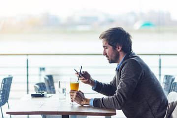 Attractive middle aged businessman using phone in cafe bar