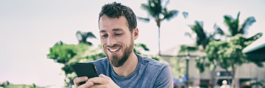 Smartphone Man Using Mobile Phone Texting Sms Text Message Outside In Summer Background. Young People Lifestyle Banner Panorama. Happy Casual Guy Smiling Holding Cellphone Using App For Social Media.