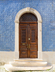 Lisbon - Portugal, facade of a house covered with typical blue tiles, azulejos, and ancient decorated wooden door