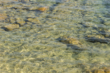 Fototapeta na wymiar shallow bottom of sea stone rocky shoreline fuzzy water surface background