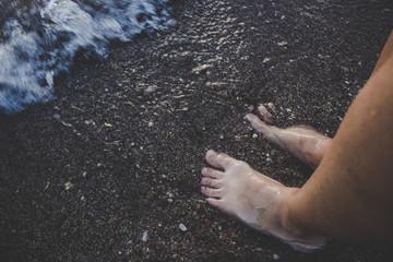 human male boy bare feet on natural reservoir shoreline with fuzzy waves