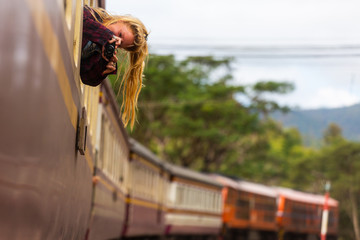 Fototapeta na wymiar Backpacker hippie girl looks through the train car window