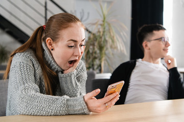 SMS. Closeup portrait funny shocked anxious scared young girl looking at phone seeing bad news photos message with disgusting emotion on face. Human reaction, expression