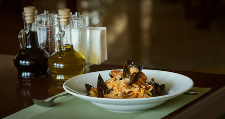 Pasta with seafood in restaurant with oil and napkins in the background