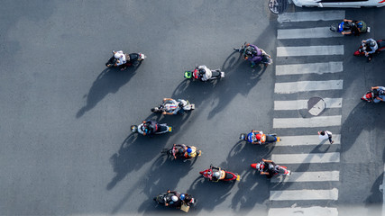 top aerial view of blur bikers ride the motorcycles to pass pedestrian crosswalk on road with the traffic pattern signage on the street