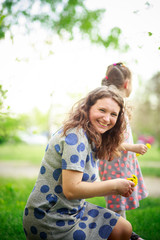 Happy mother on walk with children. Mom weaves wreath of dandelions for her daughter. Happy Mothers day