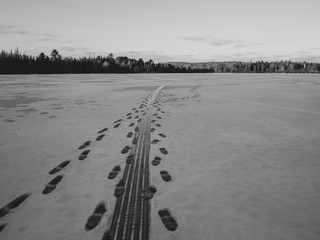 tracks in the snow on a frozen lake in winter, black and white.