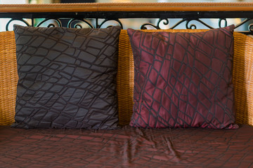 Modern red and brown velvet checkered fabric cushion pillows on rattan wicker chair interior decoration