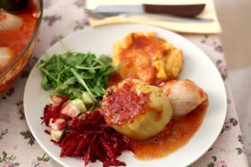 Pepper, onion and zucchini stuffed with various vegetables and roasted with tomato sauce, served on a table. Selective focus.