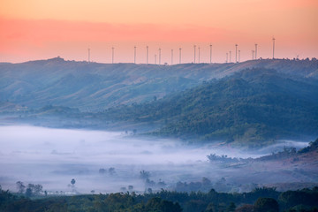 Fototapeta na wymiar wind farm at top of the mountain range with white fog float over ground