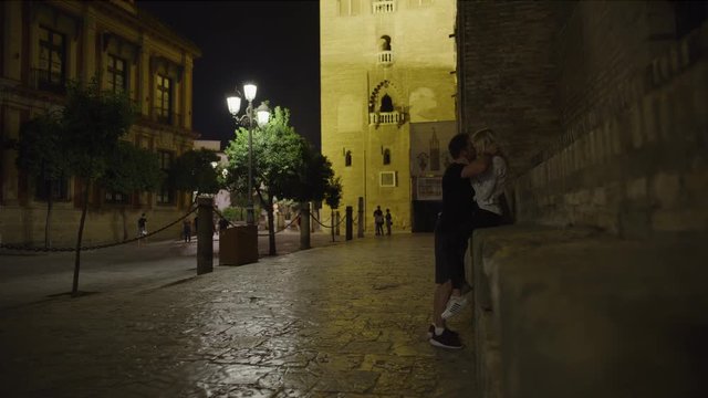 Romantic couple leaning on building hugging and kissing at night / Seville, Sevilla, Spain
