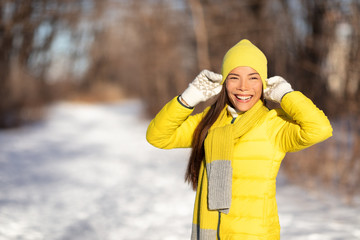 Naklejka premium Winter woman smiling emotion outside in nature forest Asian girl happy wearing yellow hat and gloves for cold season. Walk in nature park in snow.
