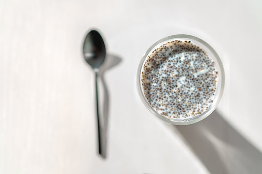 Chia Seeds Pudding In Almond Milk - Healthy Vegan Eating Breakfast In Morning. Top View Of Kitchen Table With Black Spoon And Glass Cup.