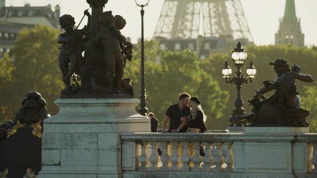 Happy couple kissing near statues on Pont Alexandre / Paris, Ile de France, France