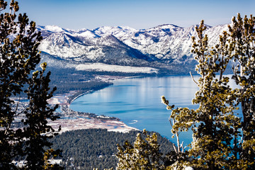 Aerial view of Lake Tahoe on a sunny winter day, Sierra mountains covered in snow visible in the...