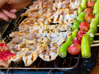 Grilling chicken kabobs on flaming grill, chicken shish kebab on bbq grill in sauce on skewers with tomatoes and peppers