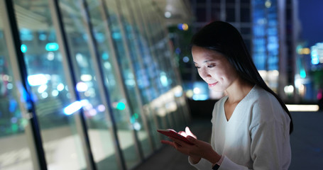 Woman look at smart phone in city at night