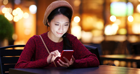 Woman use of smart phone at outdoor coffee shop at night
