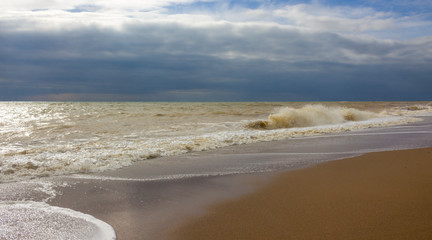 Fototapeta na wymiar View of storm seascape. Sandy beach during a storm at dusk. sea wave crashes on shore