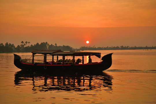 A boat sailing over alleppey backwaters in Kerala during sunrise.