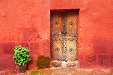 Fototapeta na wymiar Old wooden door on the red wall. Santa Catalina monastery in Arequipa, Peru