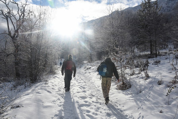 Winter hiking. Walking to mountain into the sun