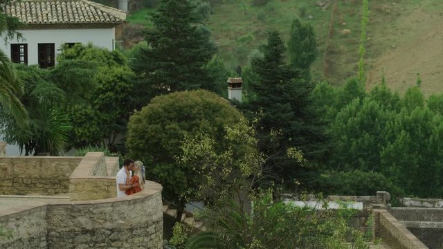 Distant couple hugging and kissing at Jardines de Cuenca / Ronda, Malaga, Spain