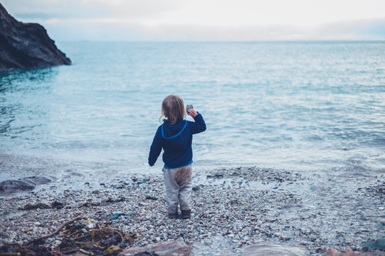 Little toddler throwing rocks in the sea