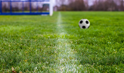 Fragment of a field with a white line on the green grass with blurred soccer ball . Focus selective..
